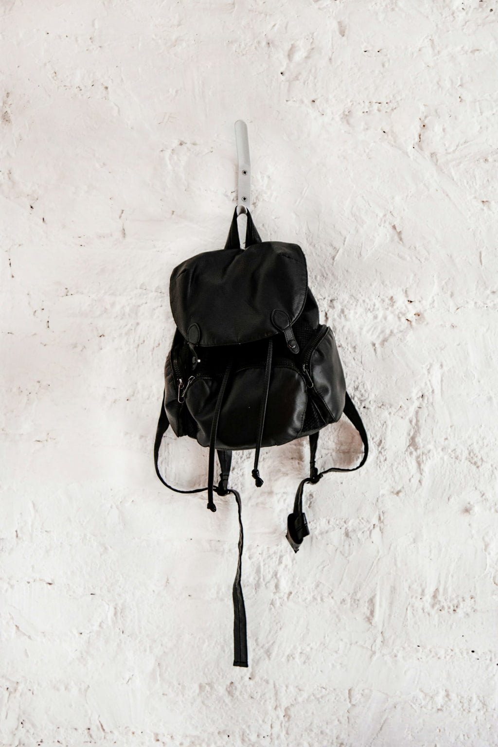 Black mini backpack hanging on a wall