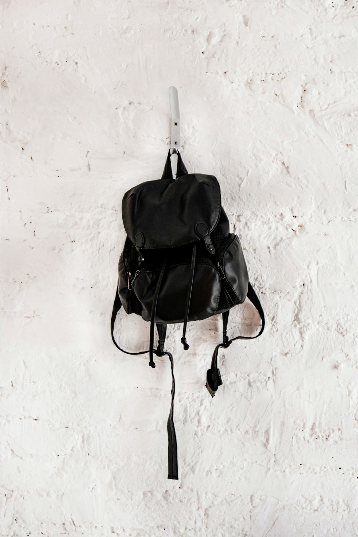 Black mini backpack hanging on a wall